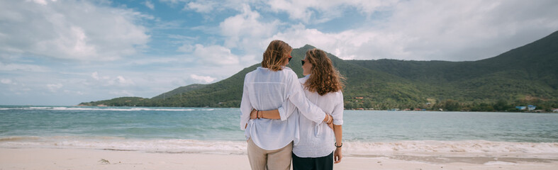 A pair of girls in love cuddling on a tropical beach.