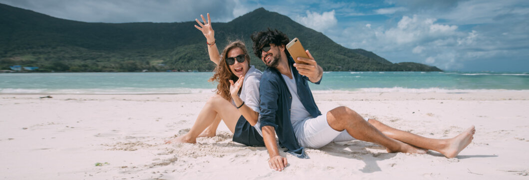 A pair of lovers take a selfie on a tropical beach.