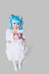 Full length portrait of cute woman in doll costume holding toy basket over gray background