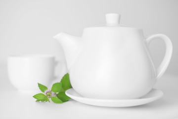 Teapot and cup decorated mint leaves. Soft focus.