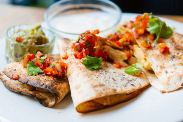 Delicious Mexican quesallidas made with chicken, tomato pieces and served with guacamole sauce.