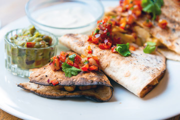 Delicious Mexican quesallidas made with chicken, tomato pieces and served with guacamole sauce.