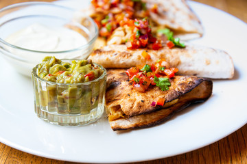 Delicious Mexican quesallidas made with chicken, tomato pieces and served with guacamole sauce.
