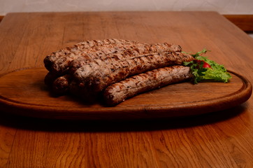 Tasty grilled sausages on wooden board