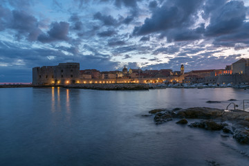 Fototapeta premium Sunset and Night view of Dubrovnik old town from seaside with reefs in foreground, Croatia