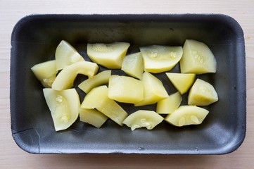 Marinated squash in a black container on a wooden table
