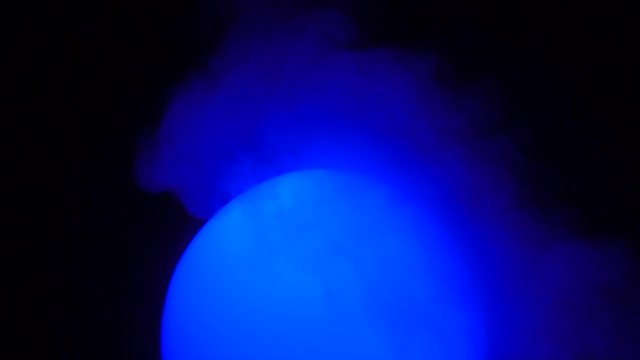 Glowing colored ball on a black background with smoke. Mystical theme