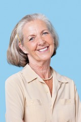 Portrait of smiling senior woman in casuals against blue background