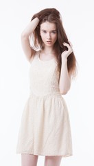 Naklejka premium Portrait of beautiful young woman in dress with hand in her hair looking away against white background