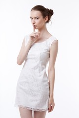 Young woman in dress gesturing to be quiet over white background