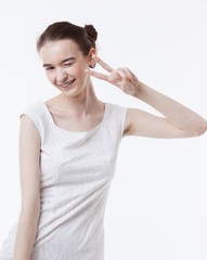 Portrait of young woman in dress gesturing peace sign over white background