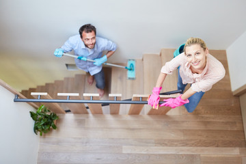 Paar mit Wischmopp beim Treppenhaus putzen