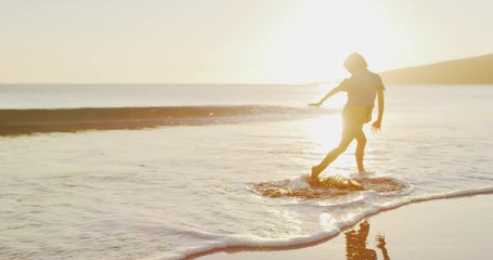 Young toddler boy running and jumping and splashing joyfully on the beach at sunset - Powered by Adobe