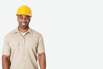 Portrait of happy young African man wearing yellow hard hat helmet over gray background