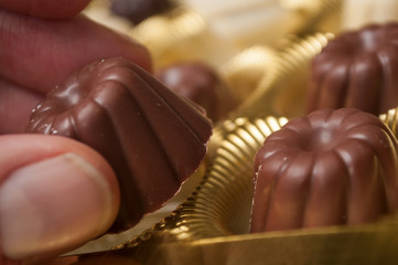 Closeup of hand of man taking a Chocolate in shaped kouglofs in golden box collection
