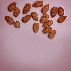 Peeled almonds on a pastel pink background. Flat lay. Copi space.
