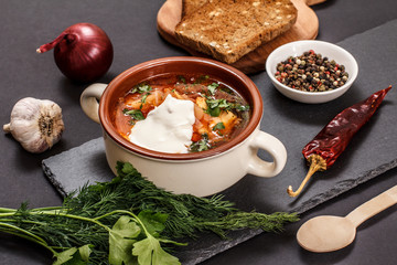 Ukrainian traditional borsch with rye bread on black background.