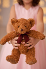 Cute girl holding a little toy brown teddy bear in a hands.