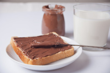 Bread toast with chocolate cream butter, jar of chocolate cream on the white background.