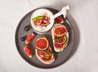 Sandwich with cream cheese, figs, honey and muesli in a glass served on the gray plate on the concrete background. Healthy food concept