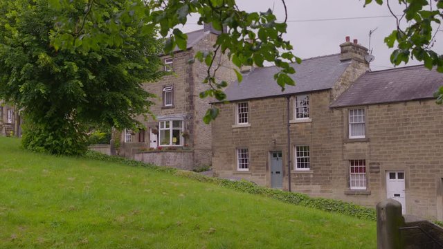 A still medium shot of 3 houses on a green hill