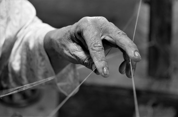 Hand of an ld woman weaving cotton