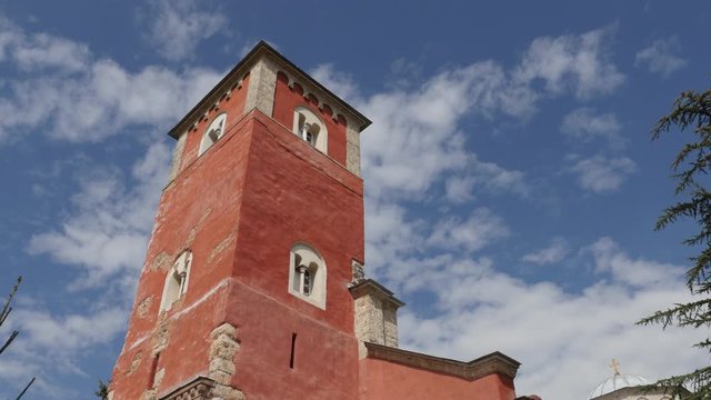 Red tower of Zica monastery and blue cloudy sky 4K tilting footage
