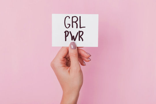 Woman's hand holding a paper with text GRL PWR