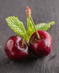 still life with cherries in a copper mug also in a steel cup and on a wooden basis
