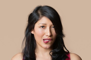 Portrait of a beautiful young woman biting lip over colored background