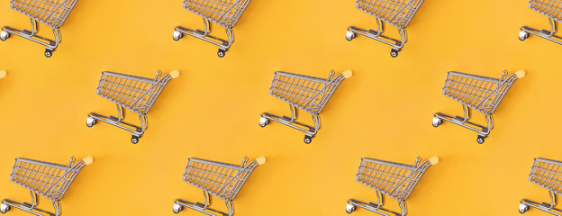 Shopping trolleys lying on a bright yellow background. © Diana Vyshniakova
