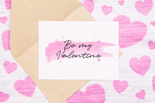 Mockup postcard and envelop on grunge white wood painted with pink heart and Be my Valentine text on postcard. Mock up for elegant design. Flat lay top view valentine's day background concept.