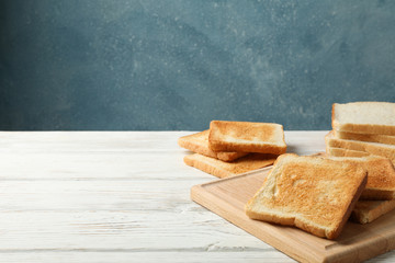 Board with toasts on white wooden background, space for text