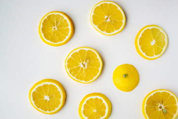 Lemon slices randomly lie on the light surface of the table.