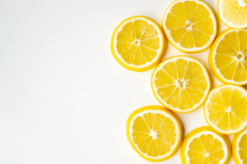 Lemon slices randomly lie on one side on a light table surface. Flat lay, close-up.
