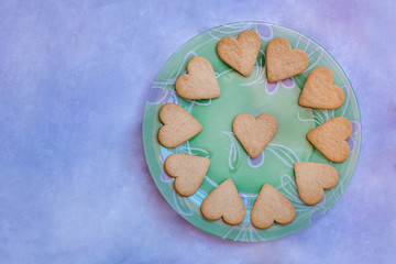 Beautiful vintage plate with heart-shaped cookies isolated on bluish background.