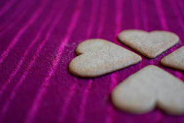 Heart-shaped cookies that in turn, together, make the shape of a four-leaf clover, isolated on a red background.