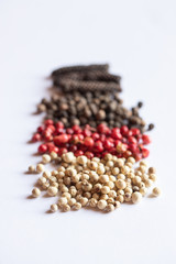 bunte pfefferkörner auf weißem grund zum würzen in der küche