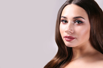 Obraz premium Portrait of young beautiful woman with perfectly clean face skin wearing professional make up. Female with long black hair. Close up, copy space background.