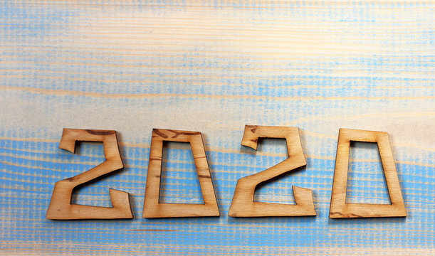 the cut numbers form the number 2020 on a partially painted wooden surface. background two thousand and twenty