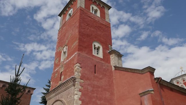 Red bell tower of Serbian Zica monastery against cloudy sky 4K tilting footage