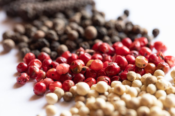 bunte pfefferkörner auf weißem grund zum würzen in der küche