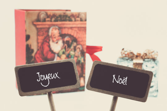 2 pancartes ardoises avec le texte joyeux noël  écrit à la craie devant des cadeaux vintage photo studio filtre vintage