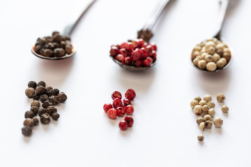 bunte pfefferkörner auf weißem grund zum würzen in der küche