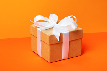 Trendy attractive minimalistic gift on the orange background. Merry Christmas, St. Valentine's Day, Happy Birthday and other holidays concept.