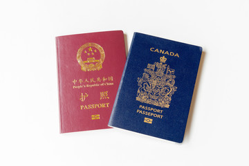 One Canadian passport and one Chinese passport on white background. 