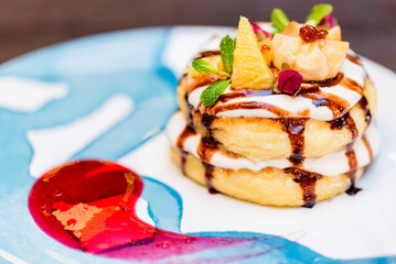 Cottage cheese pancakes or syrniki with cream, fruit jam and flower decoration