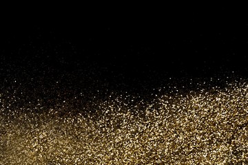 Golden glitter dispersed on a black surface, on a bottom. Christmas, new year, birthday, special occasions background, with a copy space.