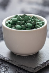 grüne Spirulina als Nahrungsergänzungsmittel auf grauem Grund