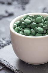 grüne Spirulina als Nahrungsergänzungsmittel auf grauem Grund